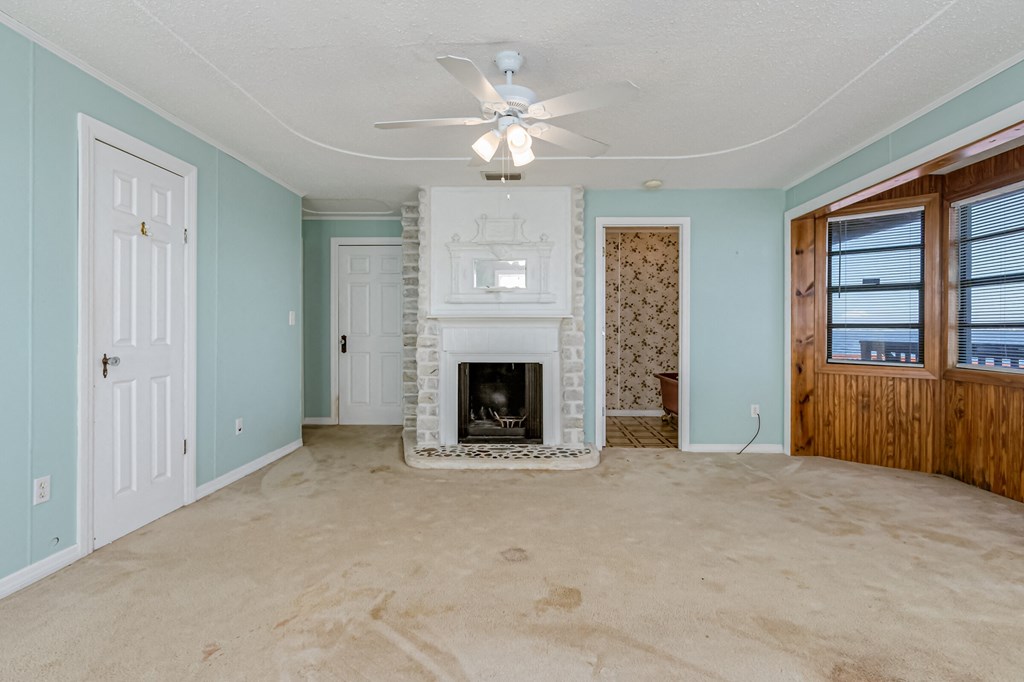 an empty living room with a fireplace and a ceiling fan