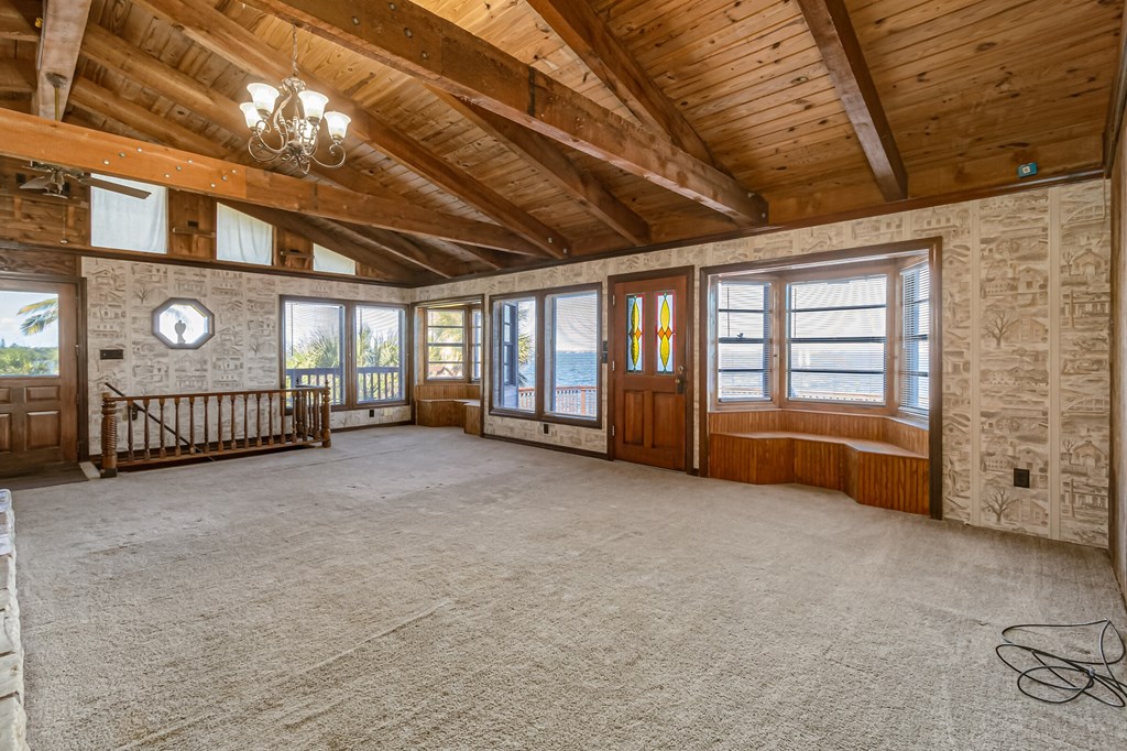 an empty living room with wood ceilings and a carpeted floor