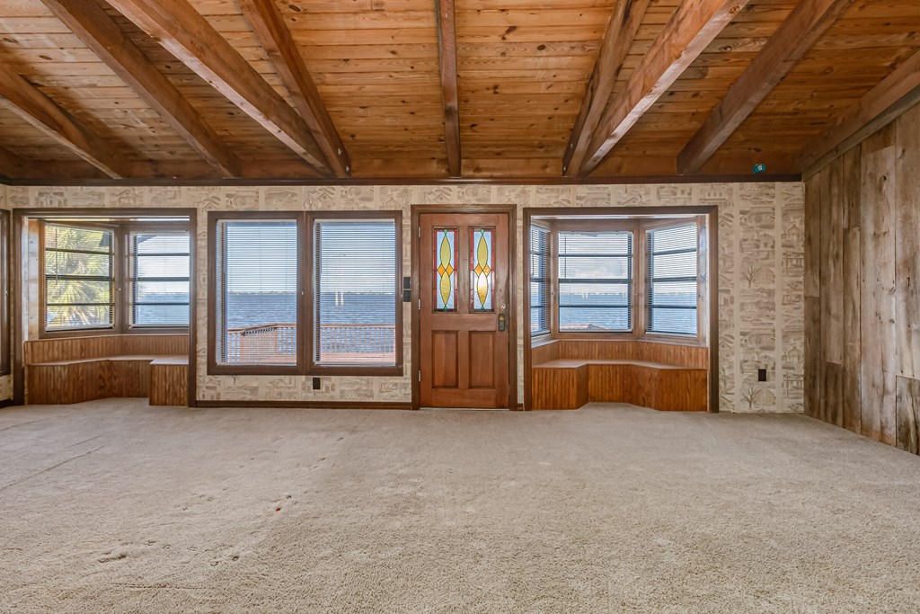 an empty living room with wooden ceilings and a view of the ocean