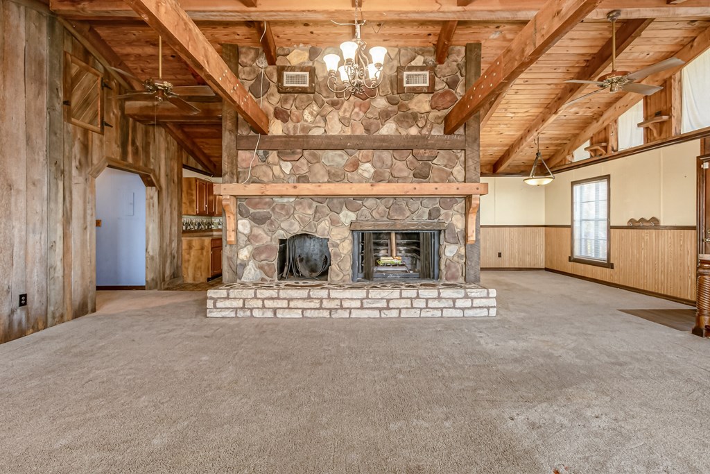 an empty living room with a stone fireplace in the center of it