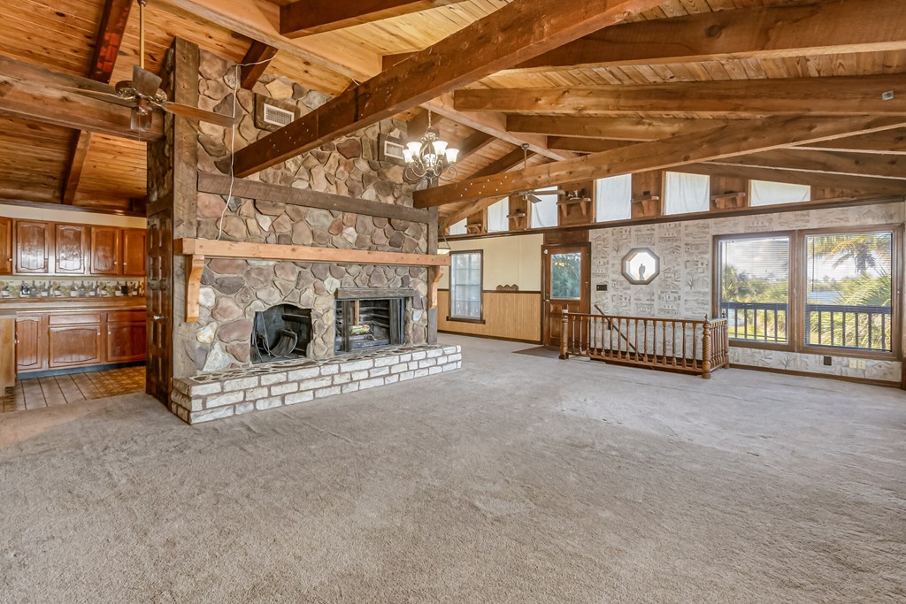 a large living room with a stone fireplace and wooden ceilings