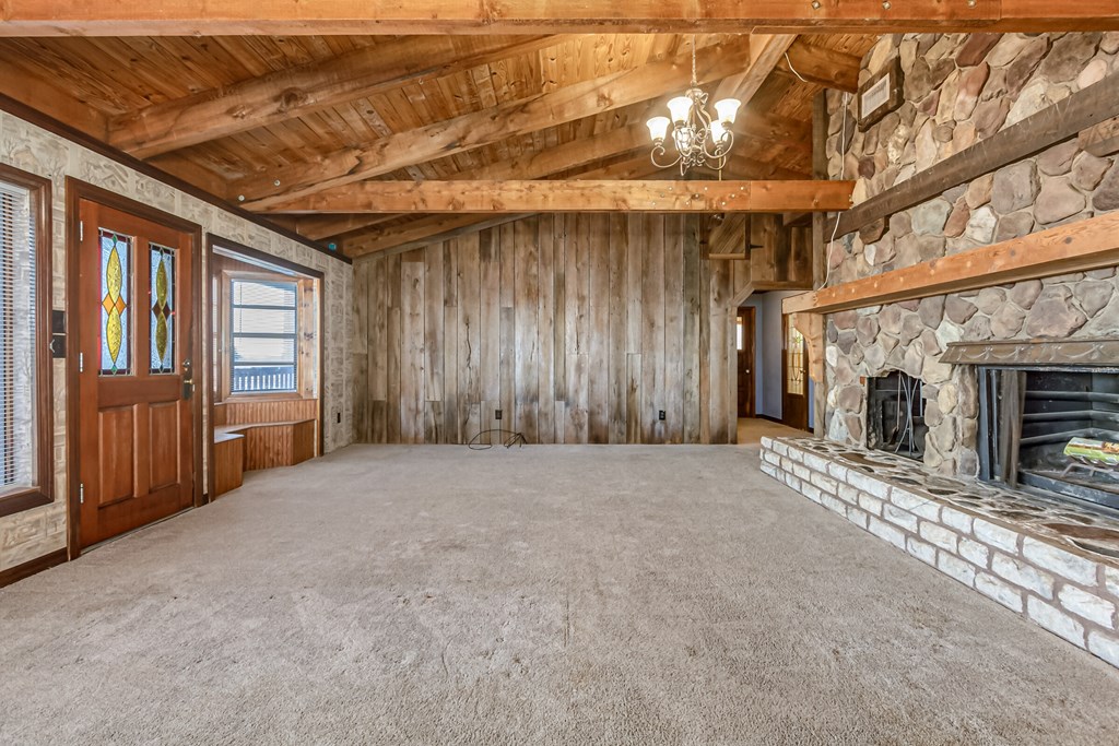 an empty living room with a stone fireplace
