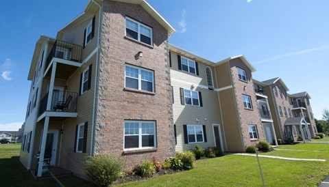 A multi-story apartment building with balconies and a clear blue sky.