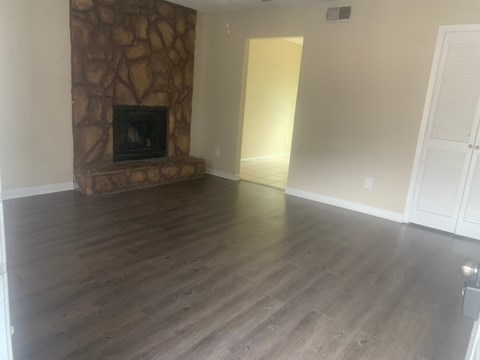 a living room with wooden floors and a stone fireplace