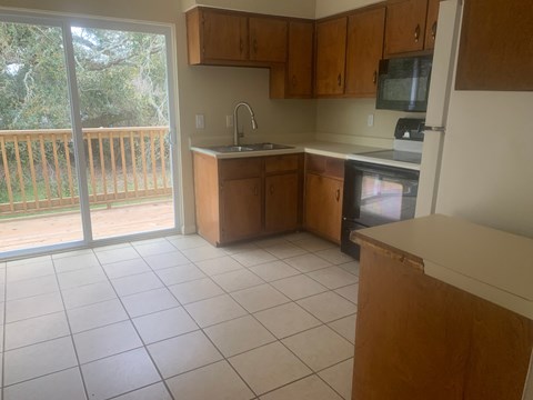 an empty kitchen with a sliding glass door to a balcony
