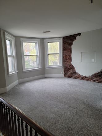 an empty living room with a brick wall and a window
