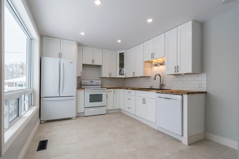 a white kitchen with white cabinets and a window