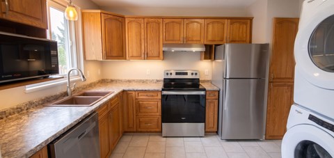A kitchen with wooden cabinets and a stainless steel refrigerator.