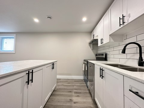 A kitchen with white cabinets and a black faucet.