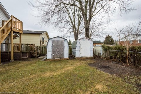 the backyard of a house with sheds and a yard and a tree