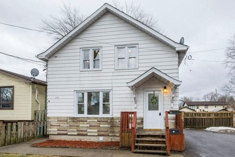 the front of a white house with a porch and stairs