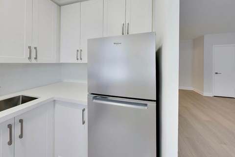 A stainless steel refrigerator in a kitchen with white cabinets.