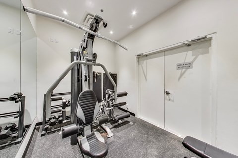 A gym room with a leg press machine and a mirror.