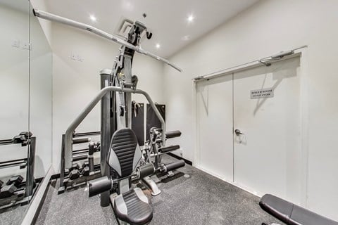 A gym room with a leg press machine and a mirror.