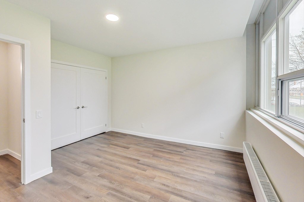 A room with a wooden floor and a window on the right side.