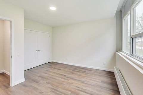 A room with a wooden floor and a window on the right side.