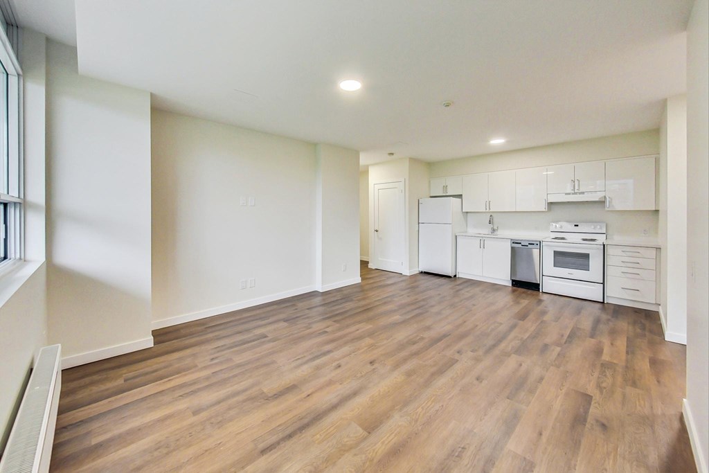 A large empty room with wooden floors and white walls.