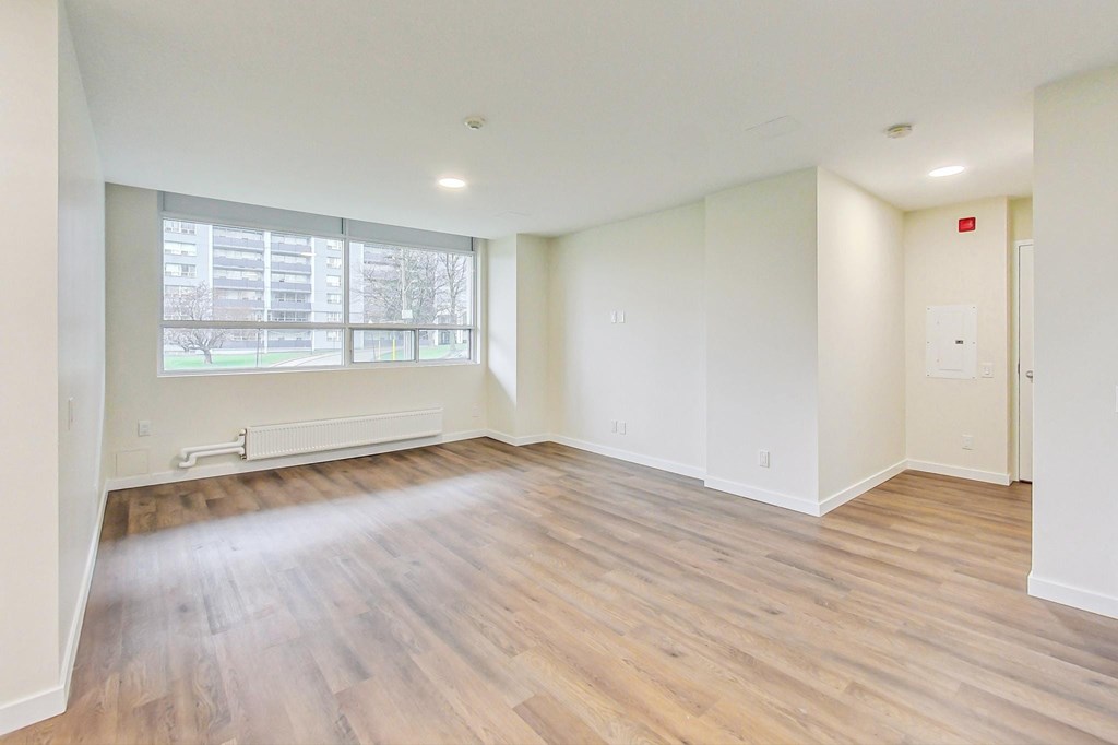 A large empty room with wooden floors and a window.