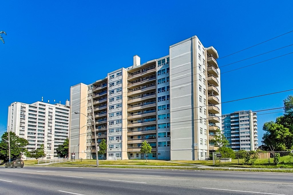 A large, modern apartment building with multiple balconies and a clear blue sky above.