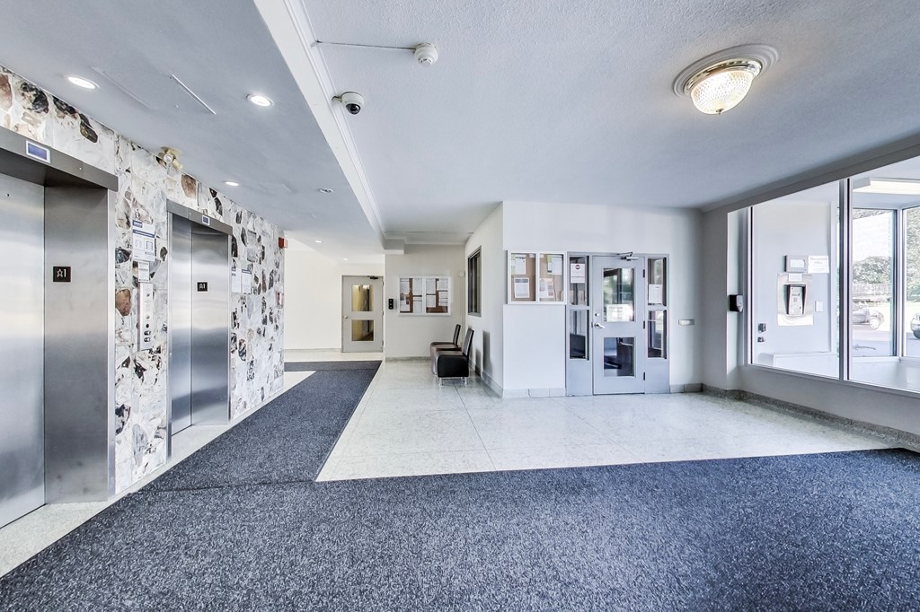 A hallway with a blue carpet and a wall with pictures on it.