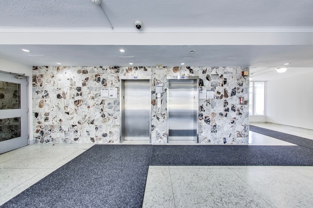 A hallway with a stone wall and two metal doors.