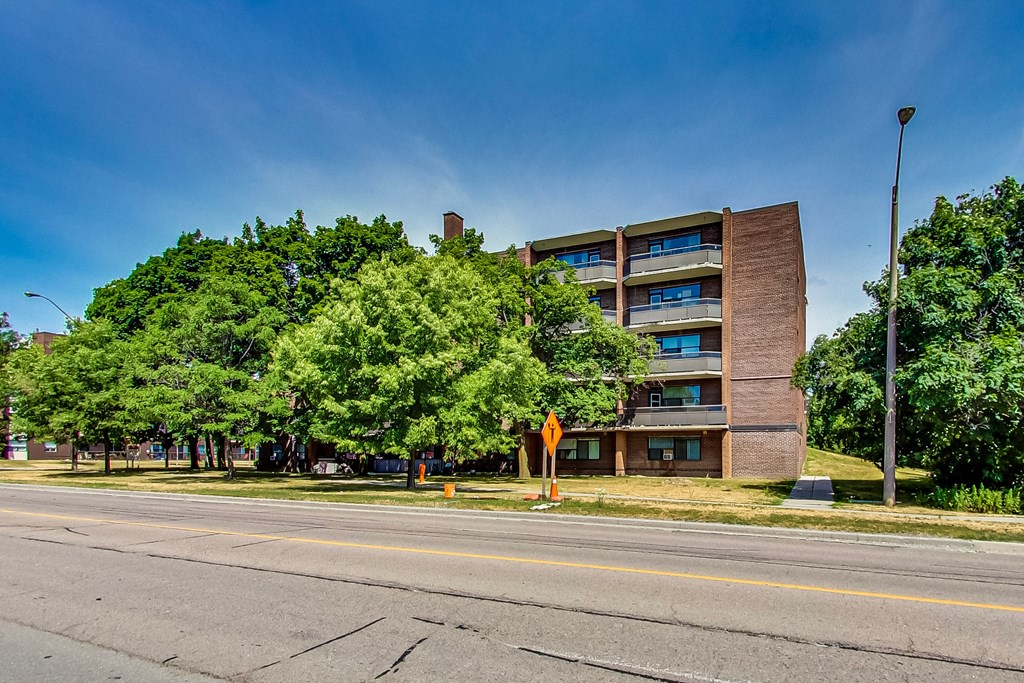 A road with a yellow sign and a building in the background.