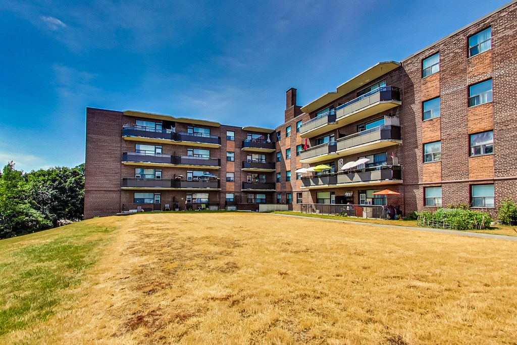 A large grassy area in front of a multi-story brick building.