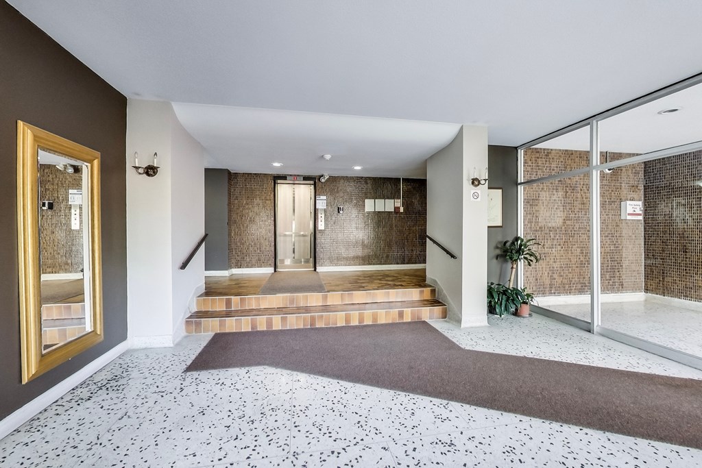 A hallway with a brown carpet and a glass wall.