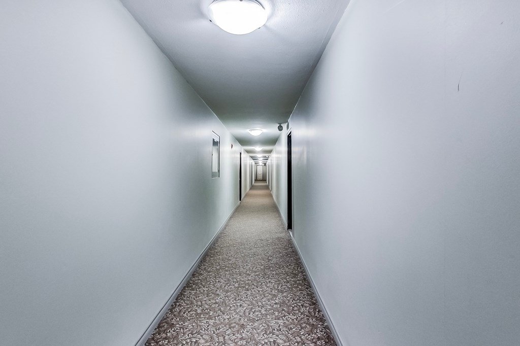 A long hallway with a carpeted floor and white walls.