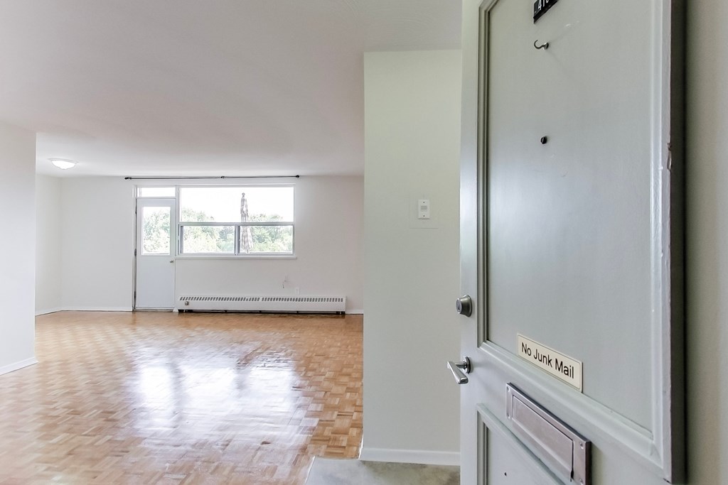 A room with a wooden floor and a door with a sign that says "No Junk Mail".