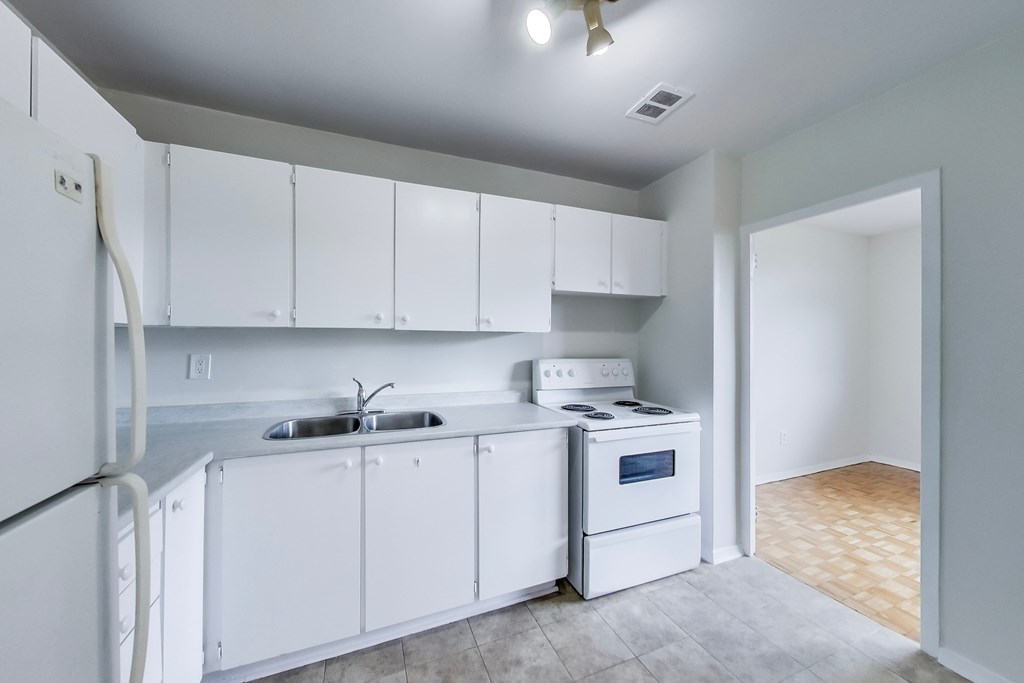 A kitchen with white appliances and cabinets.
