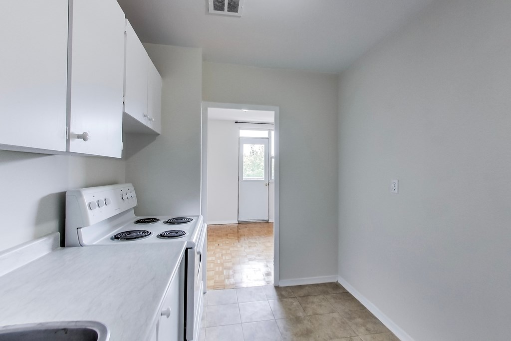A kitchen with white cabinets and a stove top oven.