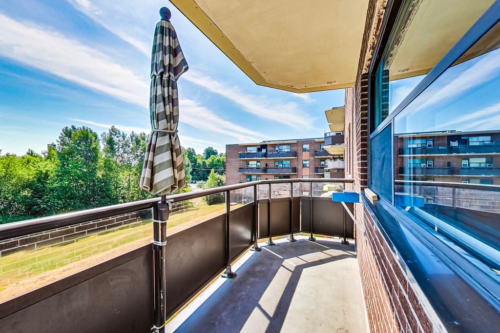 A balcony with a striped umbrella and a railing.
