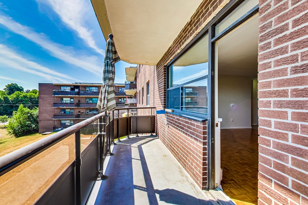 A balcony with a metal railing and a striped umbrella.