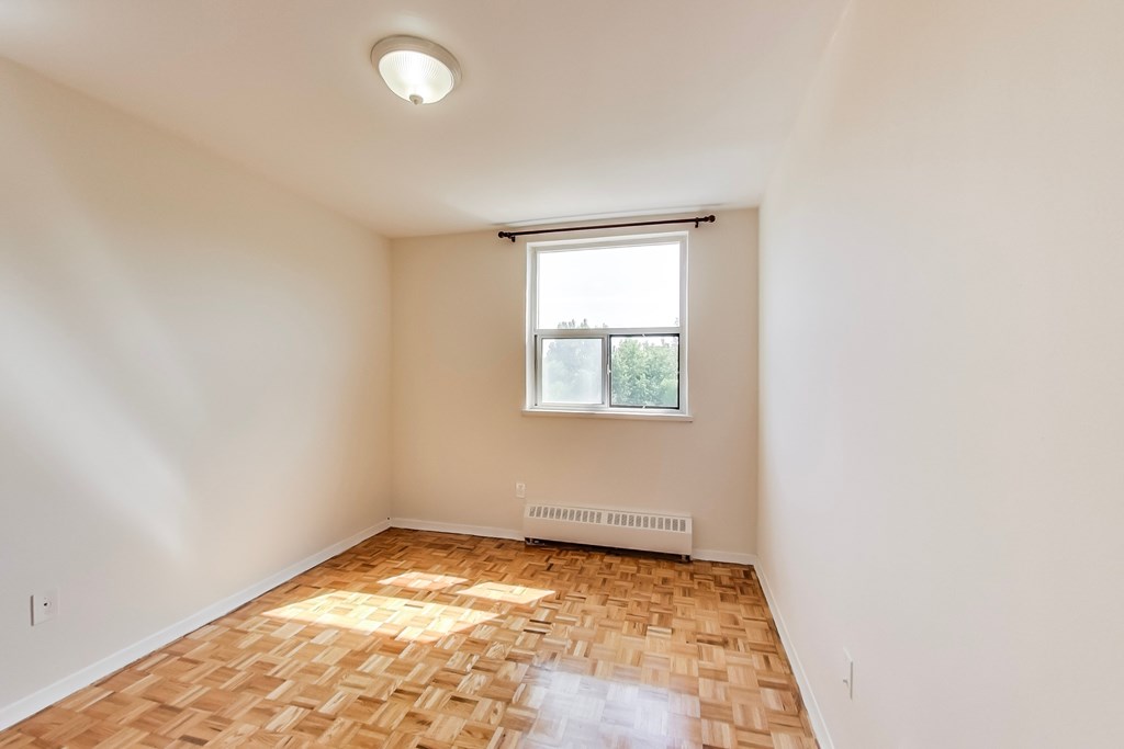 A room with a window and a radiator on the floor.