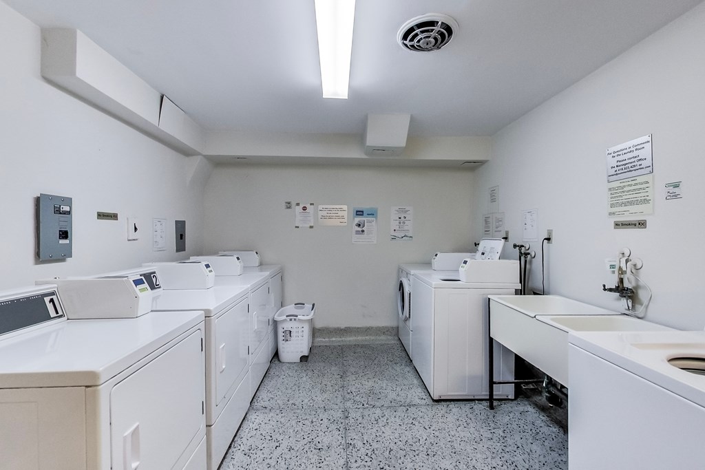 A clean, white laundry room with washers and dryers.