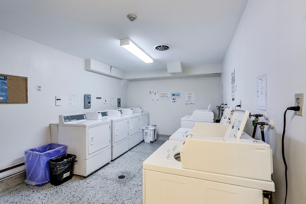 A clean, white-walled room with a collection of washing machines.