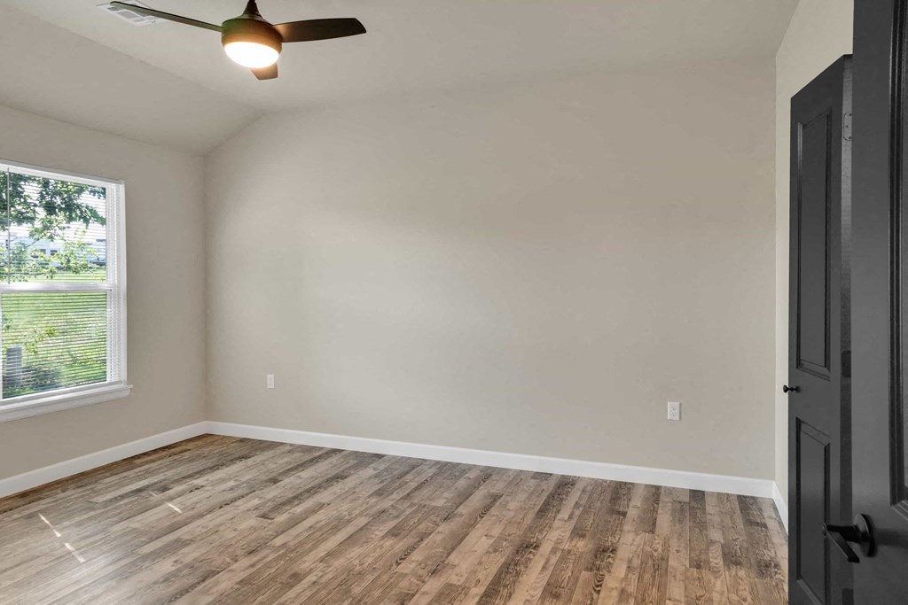an empty living room with wood floors and a window