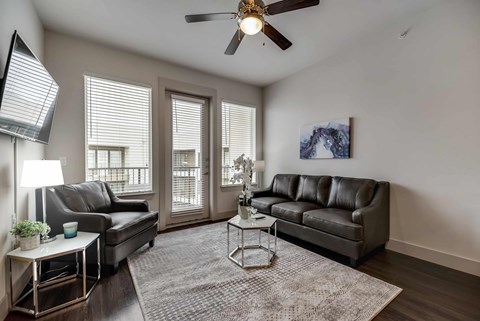 a living room with two leather couches and a ceiling fan