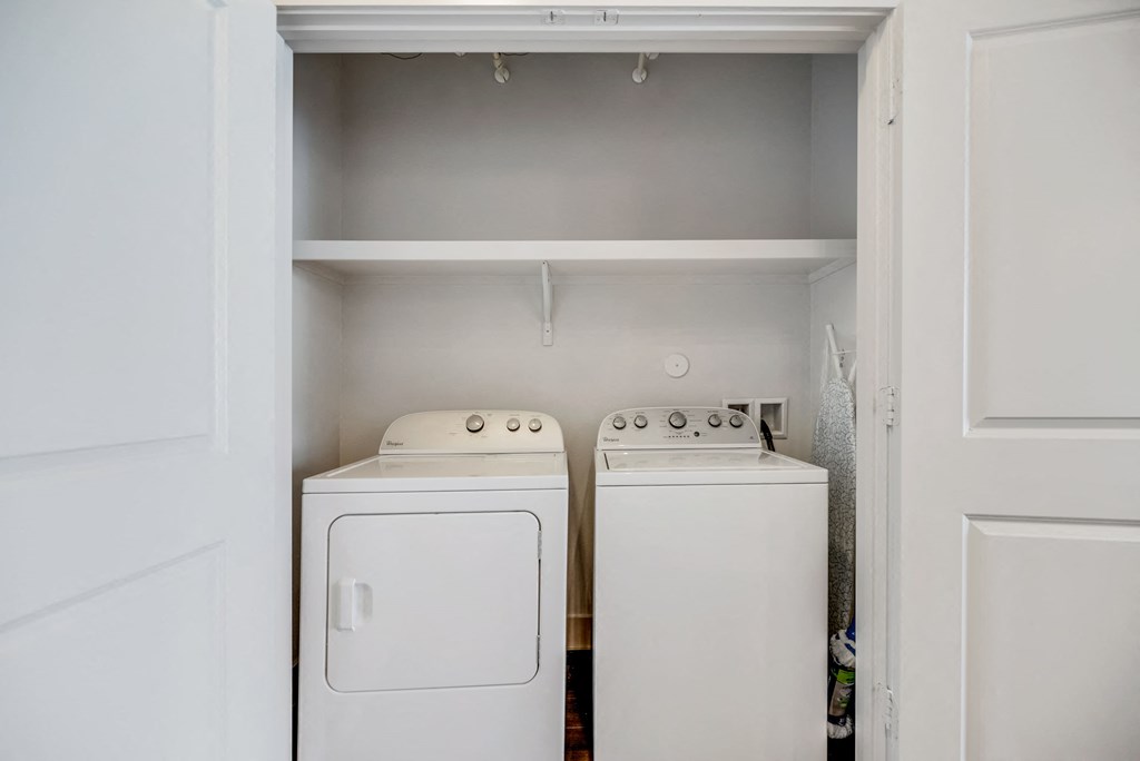 a white washer and dryer in a laundry room with white cabinets