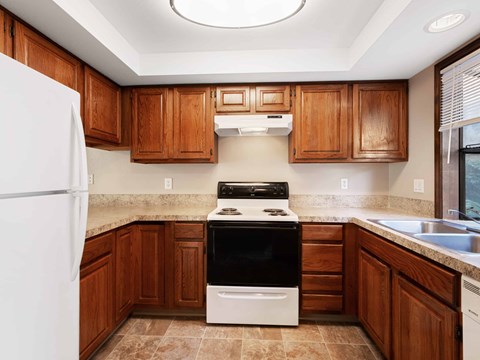 A kitchen with a white fridge, black stove and wooden cabinets.