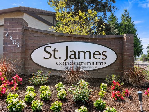 A sign for St. James Condominiums is surrounded by flowers.