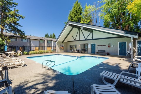 A pool with a diving board and a building in the background.
