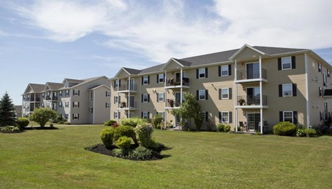 A row of townhouses with a green lawn in front.