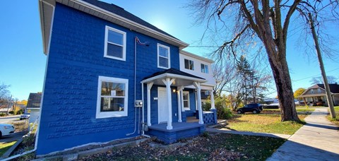 A blue house with a white door and windows.