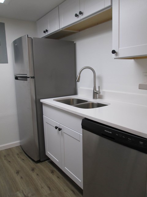 A modern kitchen with a stainless steel refrigerator and a dishwasher.