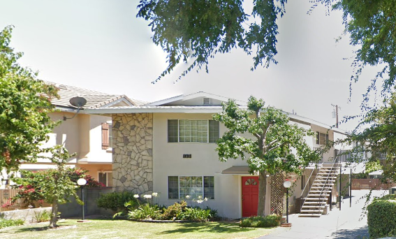 a house with a red door and a tree in front of it