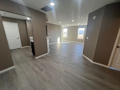 A spacious room with wooden flooring and a white door.