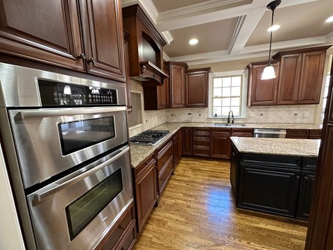 A kitchen with wooden cabinets and a stainless steel oven.
