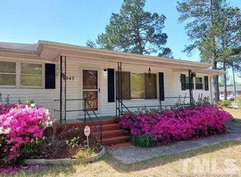 a small white house with pink flowers in front of it
